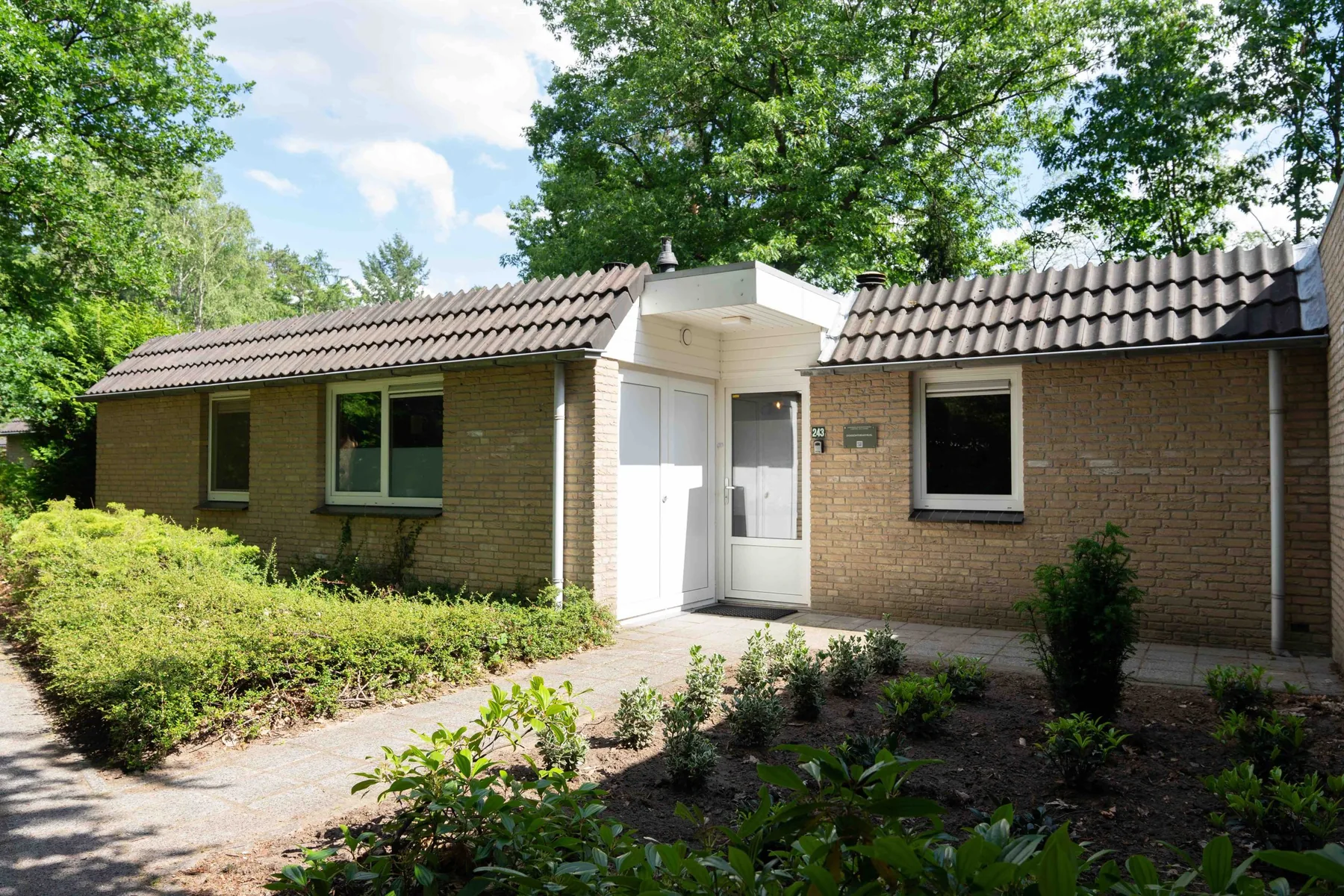 De voorkant van vakantiewoning Hert, met een sfeervolle uitstraling en groene omgeving.