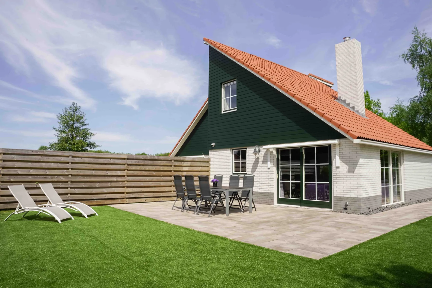 Tuin en terras van vakantiewoning Koolmees in Appelscha, een rustige en groene omheinde buitenruimte.