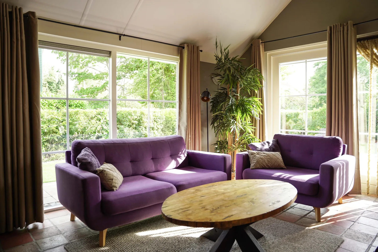 Zithoek met paarse banken en uitzicht op de tuin, vakantiewoning Koolmees in Appelscha